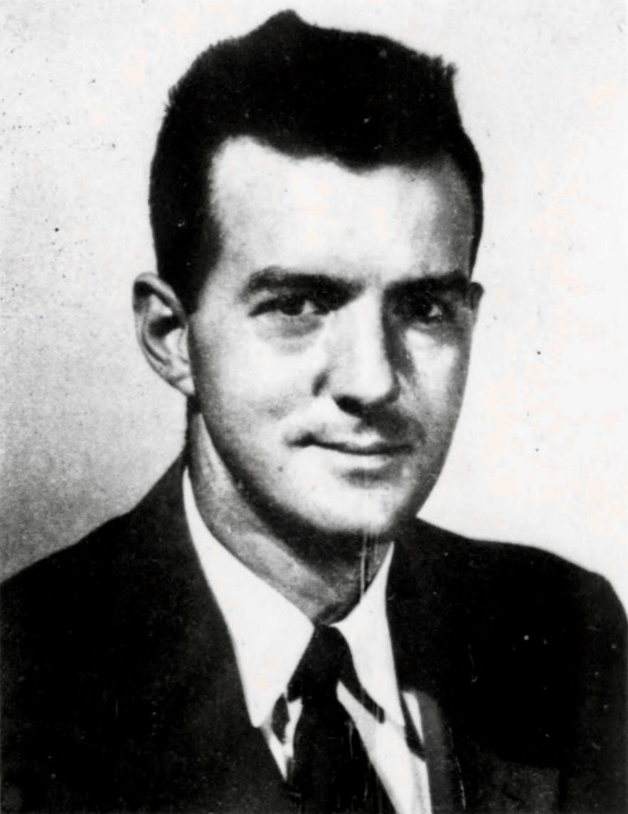 A black and white head-and-shoulders portrait of a young man with dark hair swept back, in a dark suit, white shirt and dark tie, printed as a coarse halftone