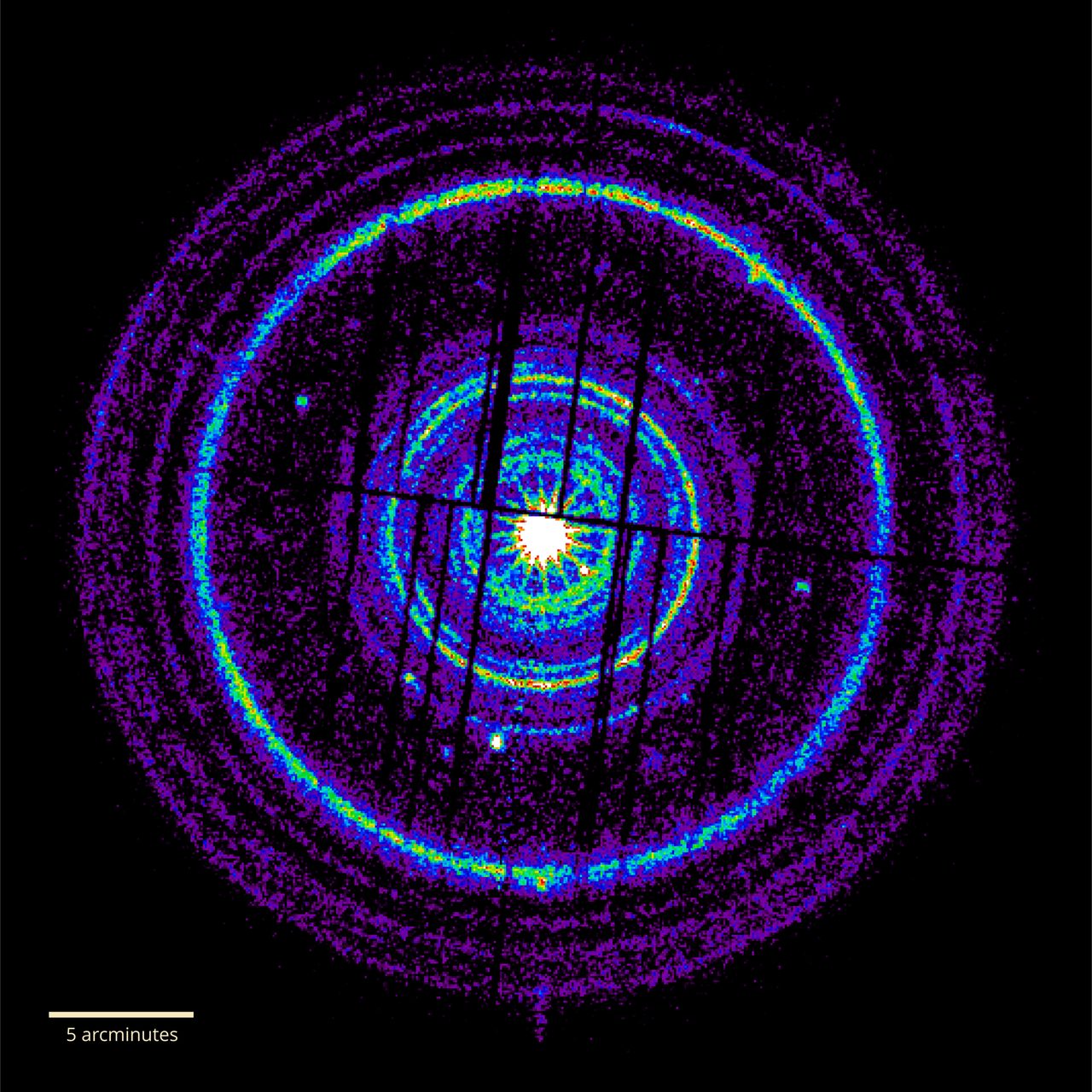 Concentric rings of X-ray light around a bright central point, crossed by straight dark stripes