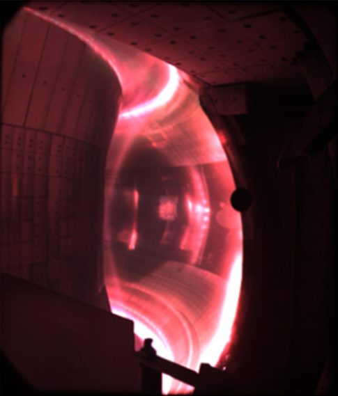 A fast-camera photograph of glowing pink-crimson plasma confined inside China's EAST tokamak