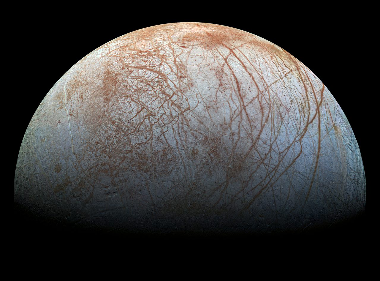 Europa's icy surface in near-natural color, showing long linear cracks and ridges across the ice shell