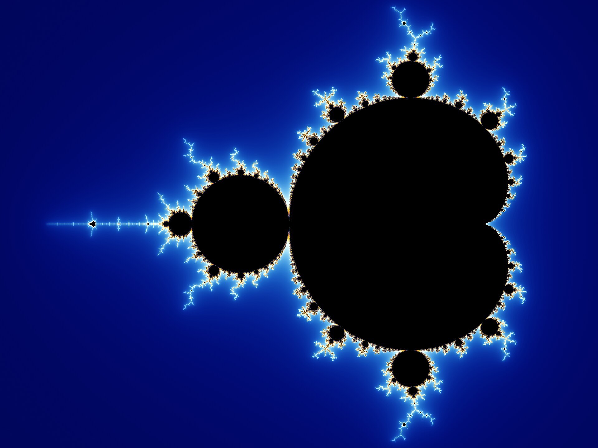 A computer render of the Mandelbrot set: a black cardioid-and-bulb shape with an intricate, self-similar filigree boundary studded with smaller bud-like copies of itself, glowing against a deep blue background