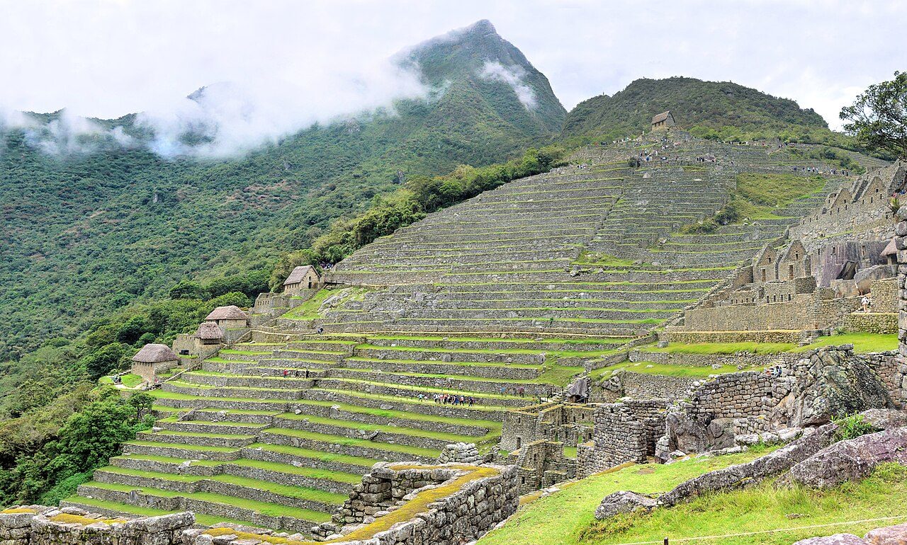 A wide view of the main agricultural terraces at Machu Picchu, with Mount Machu Picchu peak in the center and storage buildings below