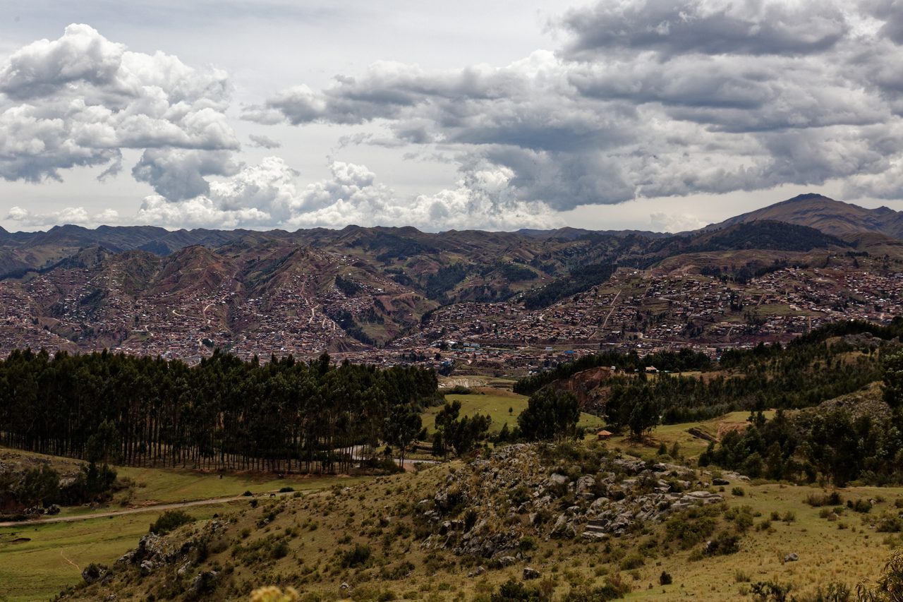 Modern Cusco filling a valley and climbing the surrounding hillsides, seen from the hilltop where Sacsayhuaman stands