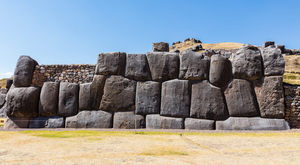The great polygonal lowest-terrace wall of Sacsayhuaman, multi-sided mortar-free stone blocks in a stepped terrace against the mountain landscape
