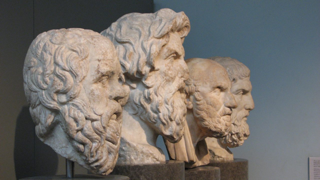 Four marble portrait heads of Greek philosophers displayed in a row in the British Museum