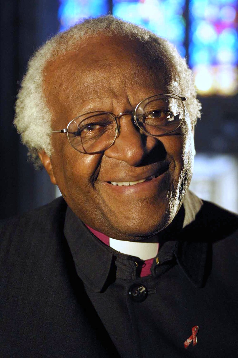 A formal portrait photograph of Archbishop Desmond Tutu, smiling, in clerical dress