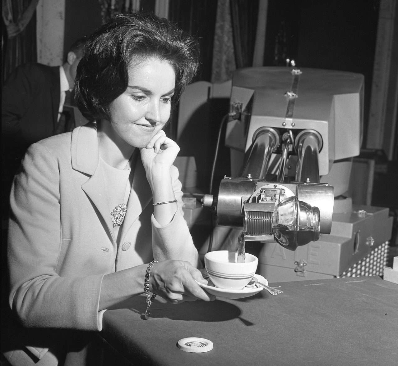 A press photograph from 1967 in which a large industrial robot arm pours coffee for a woman